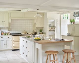 neutral painted farmhouse kitchen with wooden worktops and cream aga