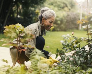 Smiling woman tends to the plants in her garden