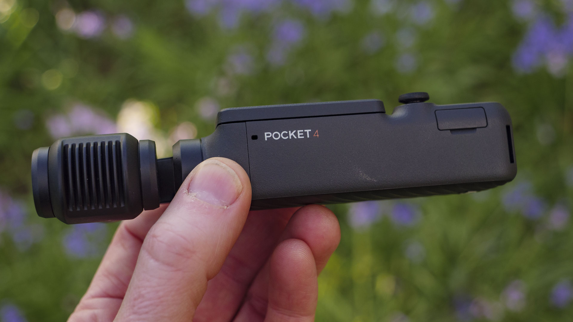 Side profile of the DJI Osmo Pocket 4 vlogging camera with natural background of bluebells