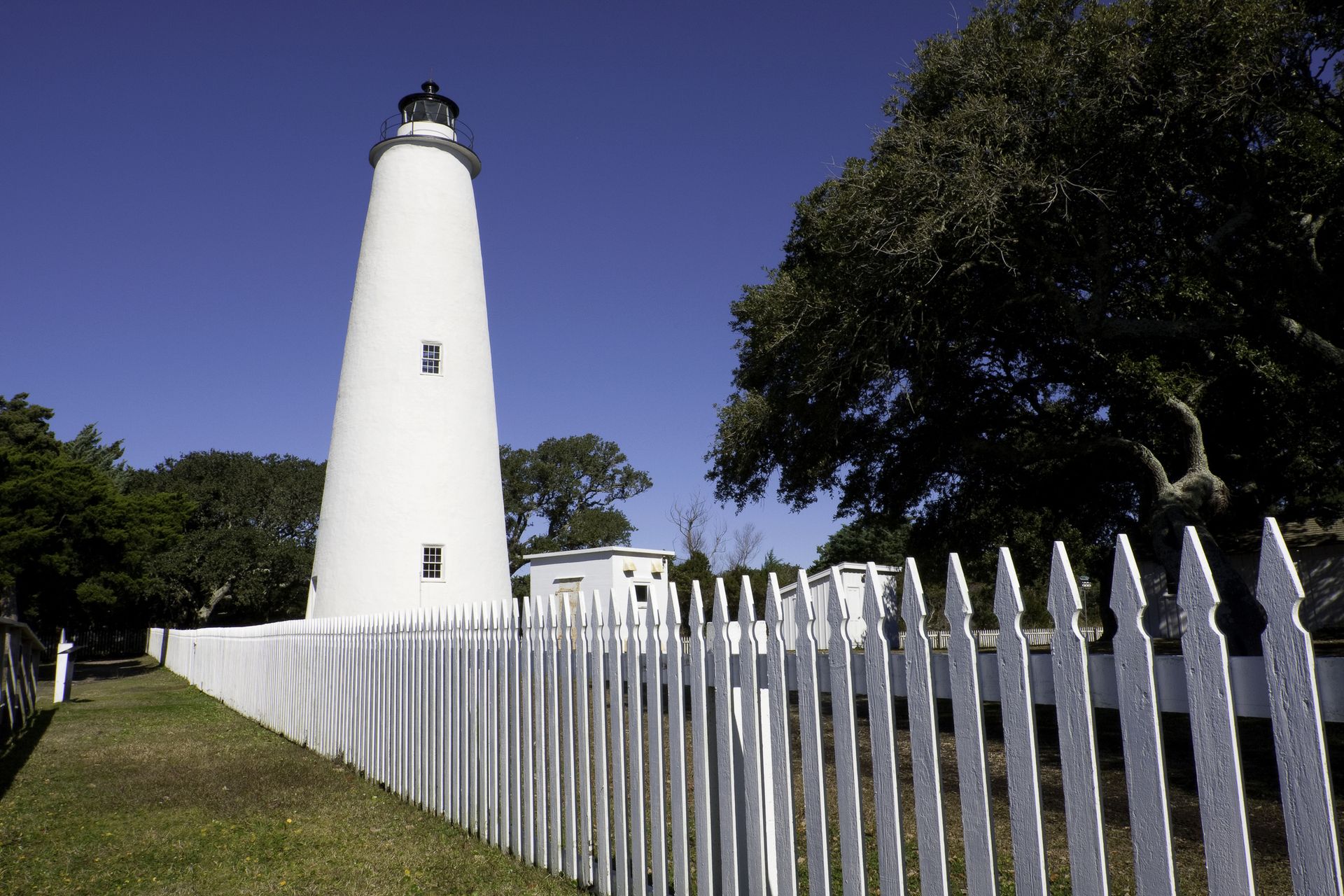 The Ocracoke Island white Lighthouse on the Outer Banks in North Carolina, with a picket fence