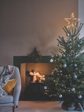 Christmas tree with simple decorations, fairy lights, armchair, candles