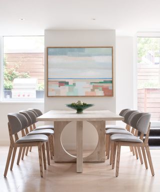 White dining room with large dining table and gray chairs