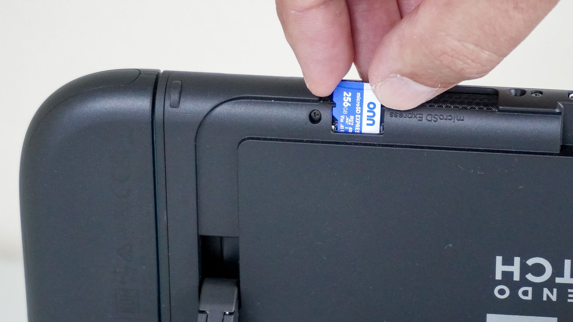 A close-up shot of a person inserting a microSD Express card into a Nintendo Switch 2 console