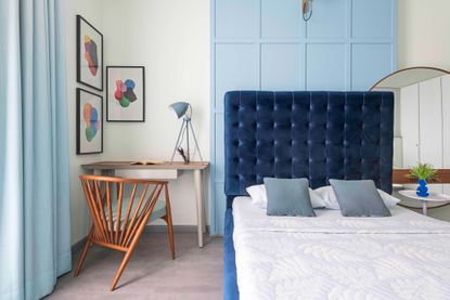 A bedroom with dark blue headboard and white linen