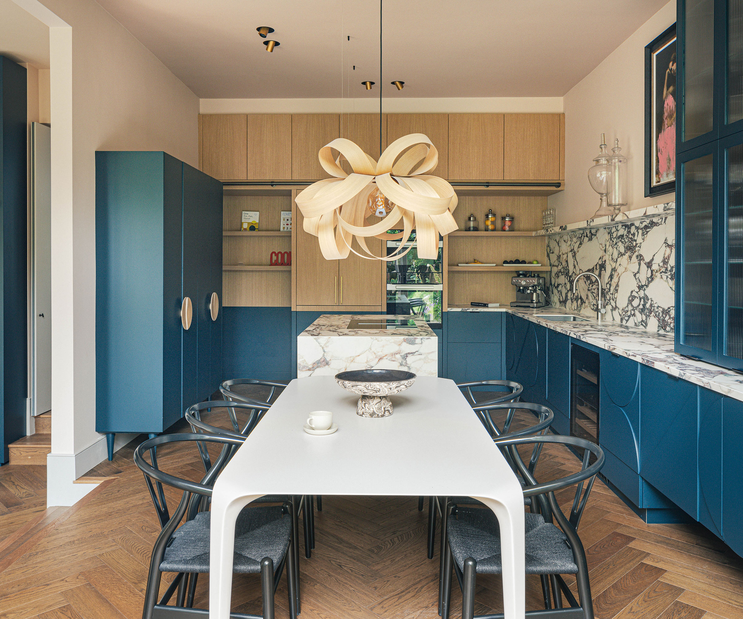 modern blue kitchen with wooden lighting and white dining table