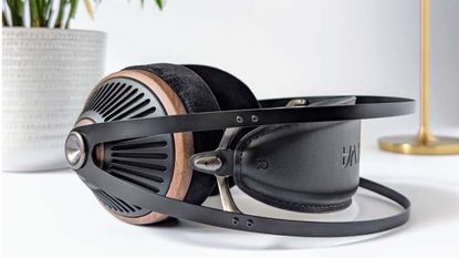 A pair of Meze Audio 105 Silva headphones on top of a white desk or unit with a plant pot and a lamp in the background