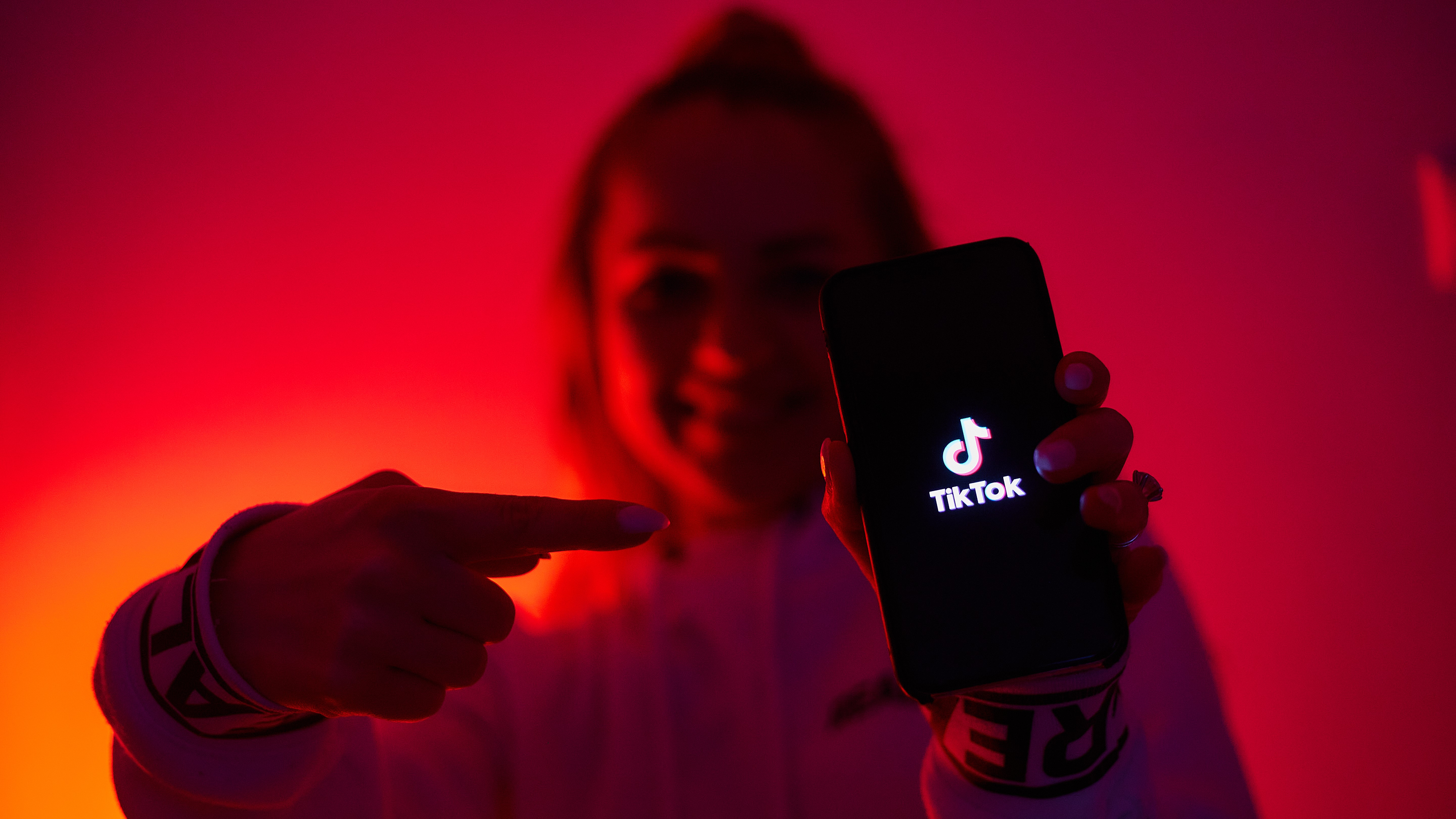 Seorang gadis dengan sisi gelap tiktok mempromosikan jejaring sosial dengan smartphone di tangan.