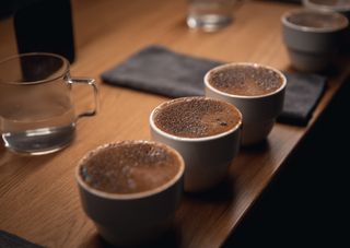 Three cups of frothy coffee on a wooden table