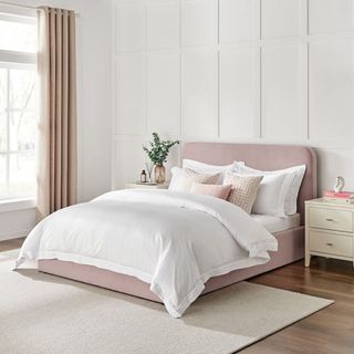 blush pink ottoman bed frame with white bedding on top