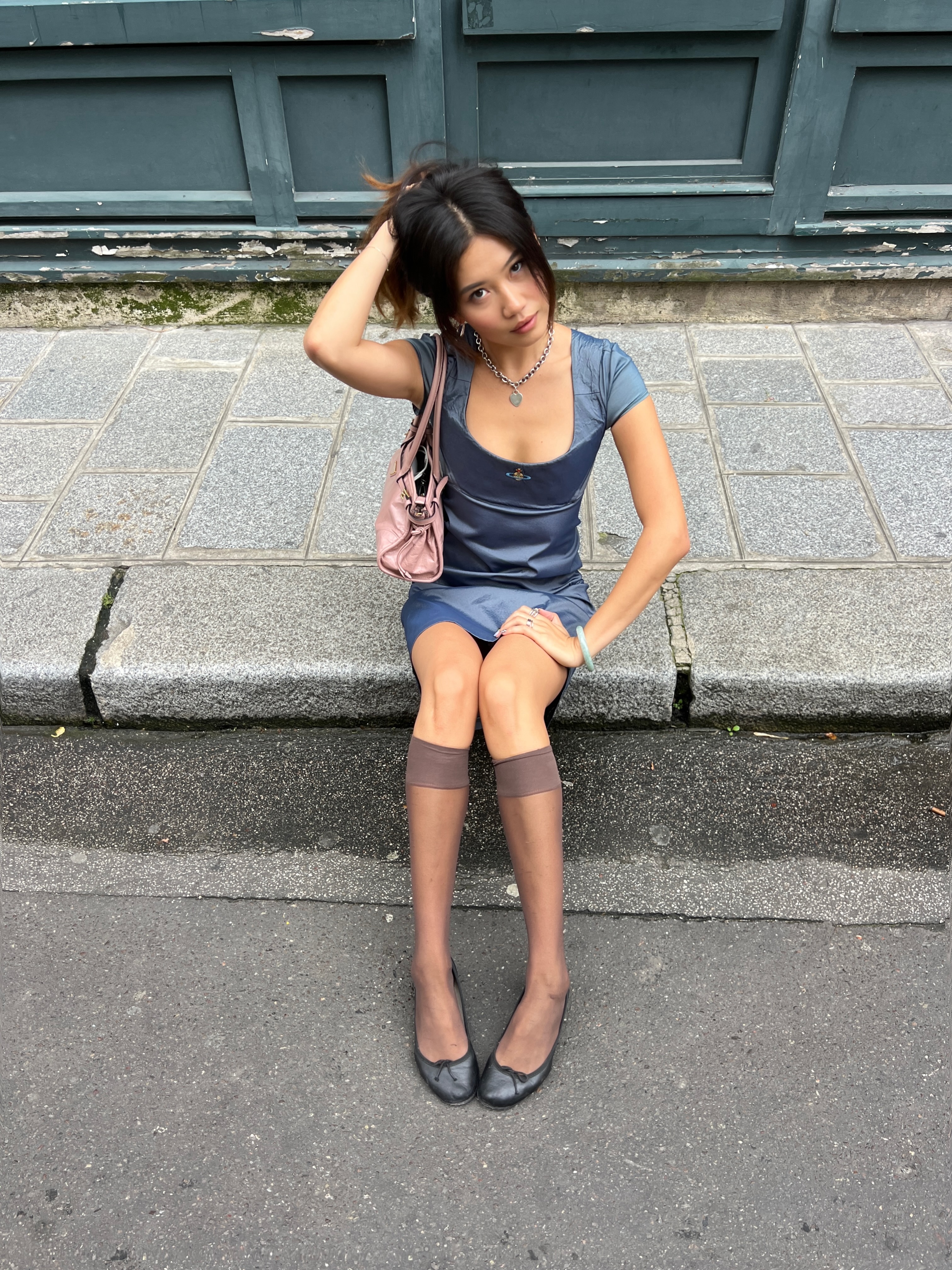 Vivian Li wearing brown sheer knee-high socks with a blue mini dress and black ballet flats at Paris Fashion Week.