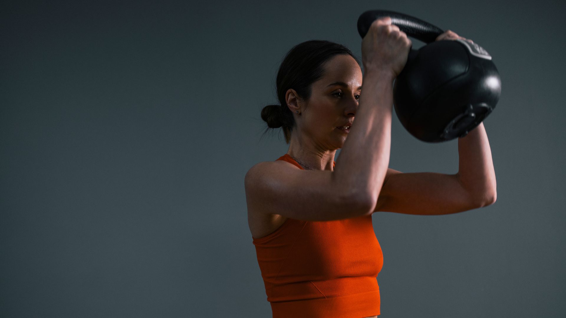 Woman holding kettlebell to do windmill exercise