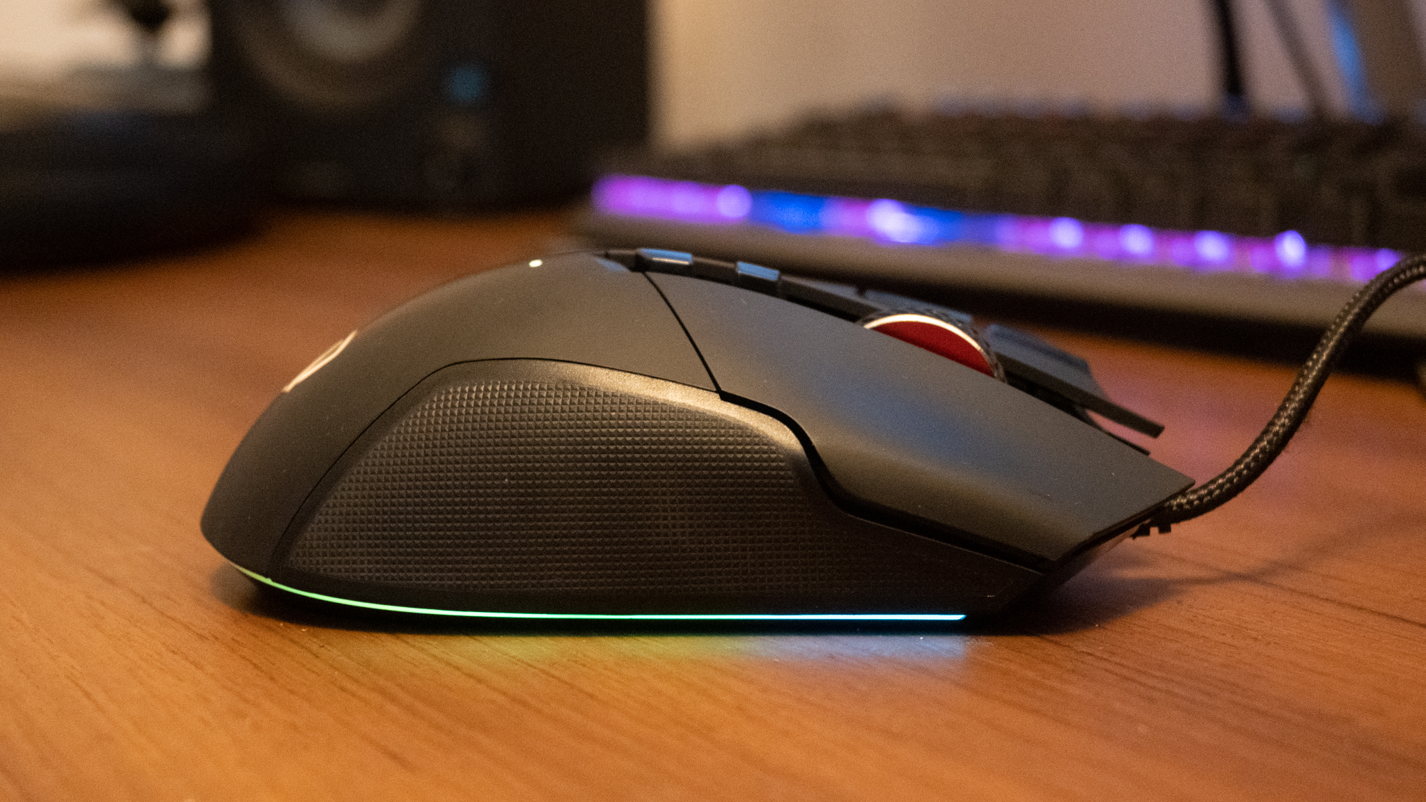 A black AOC AGM600 gaming mouse sitting on a brown wooden desk