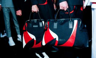 2 mens over night bags in black red and white being held by male models