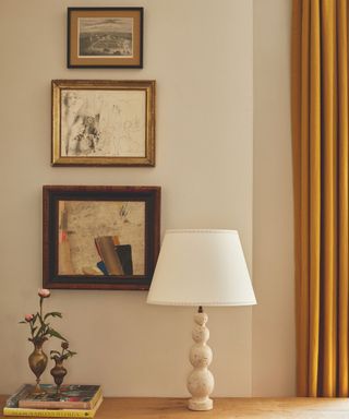 wooden bobble shape table light on surface with books, vases with flowers and art on wall in background