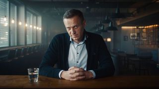 Alexei Navalny pictured looking pensive at a desk in a darkened industrial room in the Oscar-winning documentary movie simply titled Navalny.