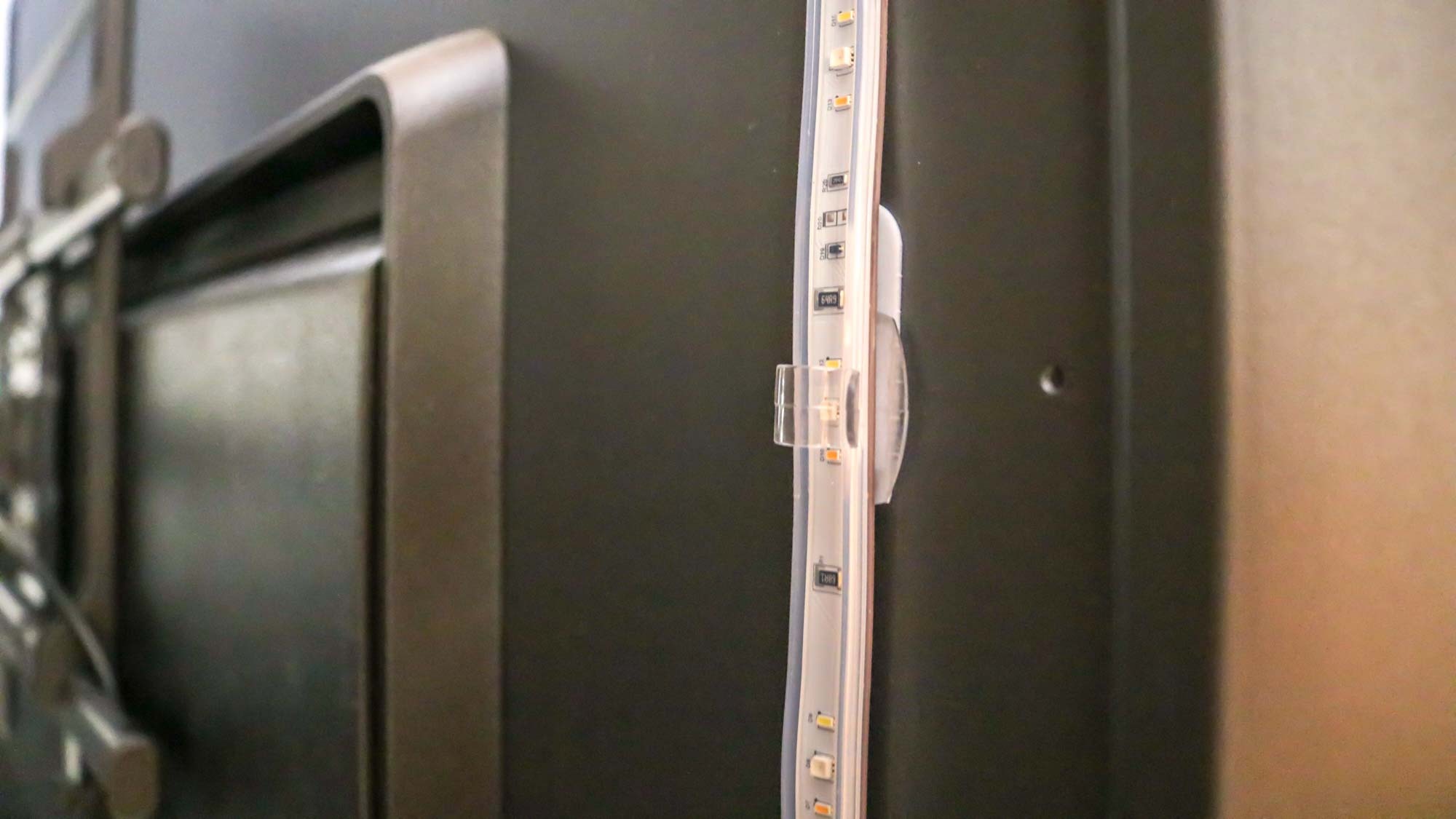 A clear clip attached to a TV holding a lightstrip