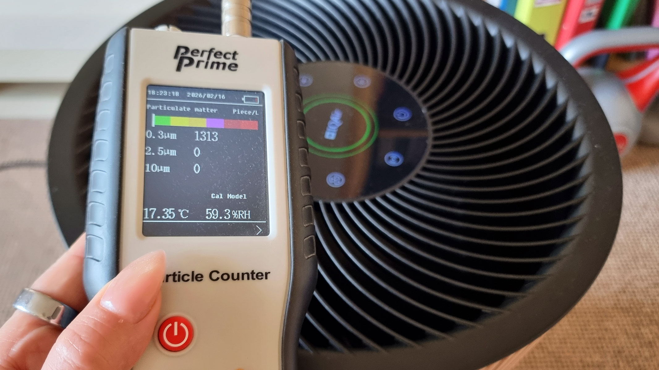 A close-up picture of our reviewer testing the IQAir Atem Earth air purifier using the Perfect Prime air particle monitor