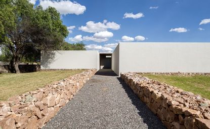 Gravel pathway leading to contemporary white building.