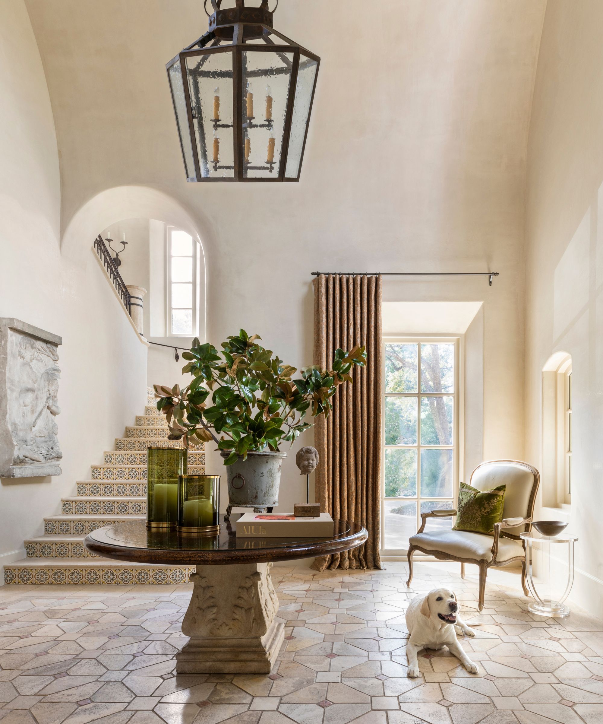 a grand tiled entryway with round hall table and a Labrador lying on the floor