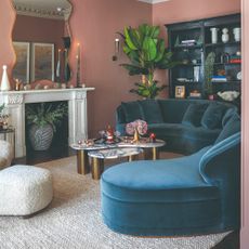 A terracotta red-painted living room with a curved blue velvet sofa