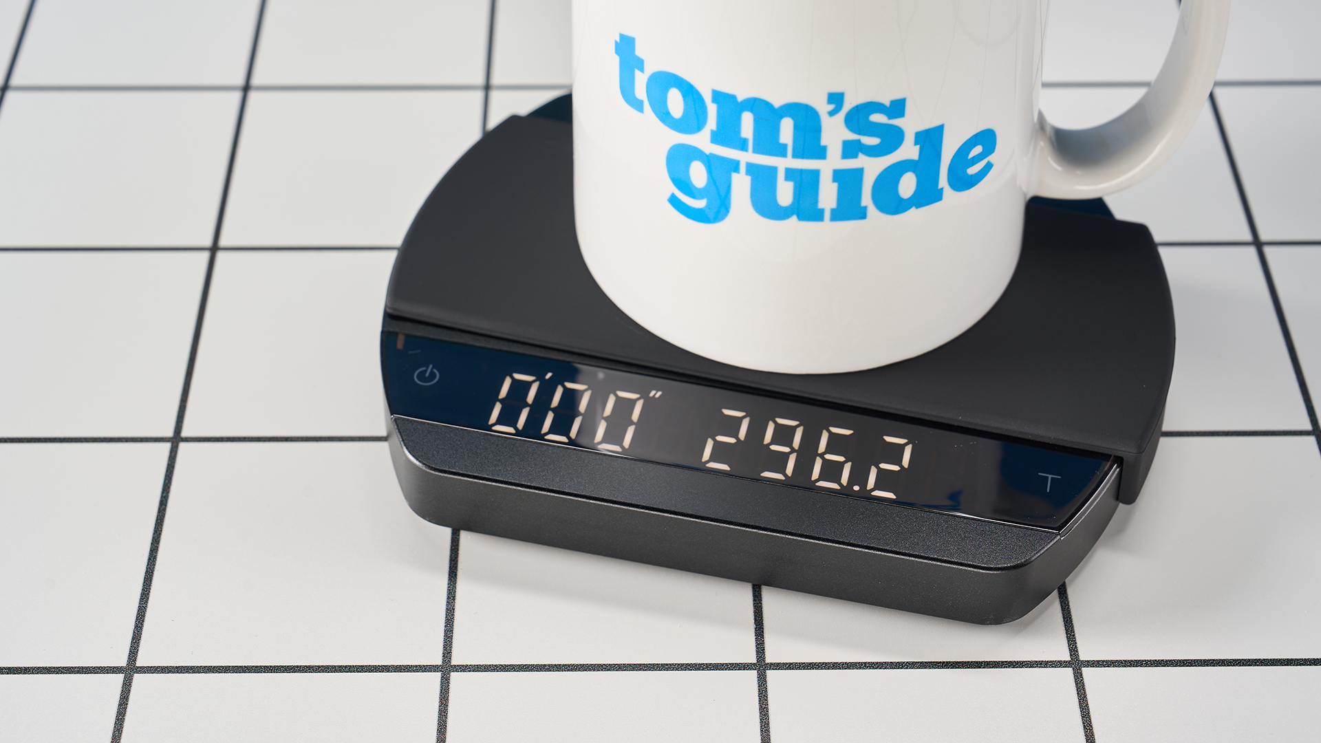 a luxury coffee scale made by Felicita Arc is photographed against a blue background with its weight, USB-C cable and silicone mat