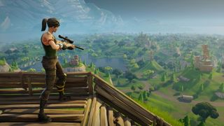 Fortnite screenshot from 2018 which shows a character perched on a building with a sniper rifle to survey a scene