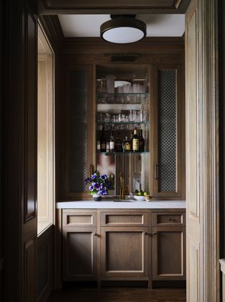 small home bar built in cabinetry, with tiny sink, glass shelving, mirror