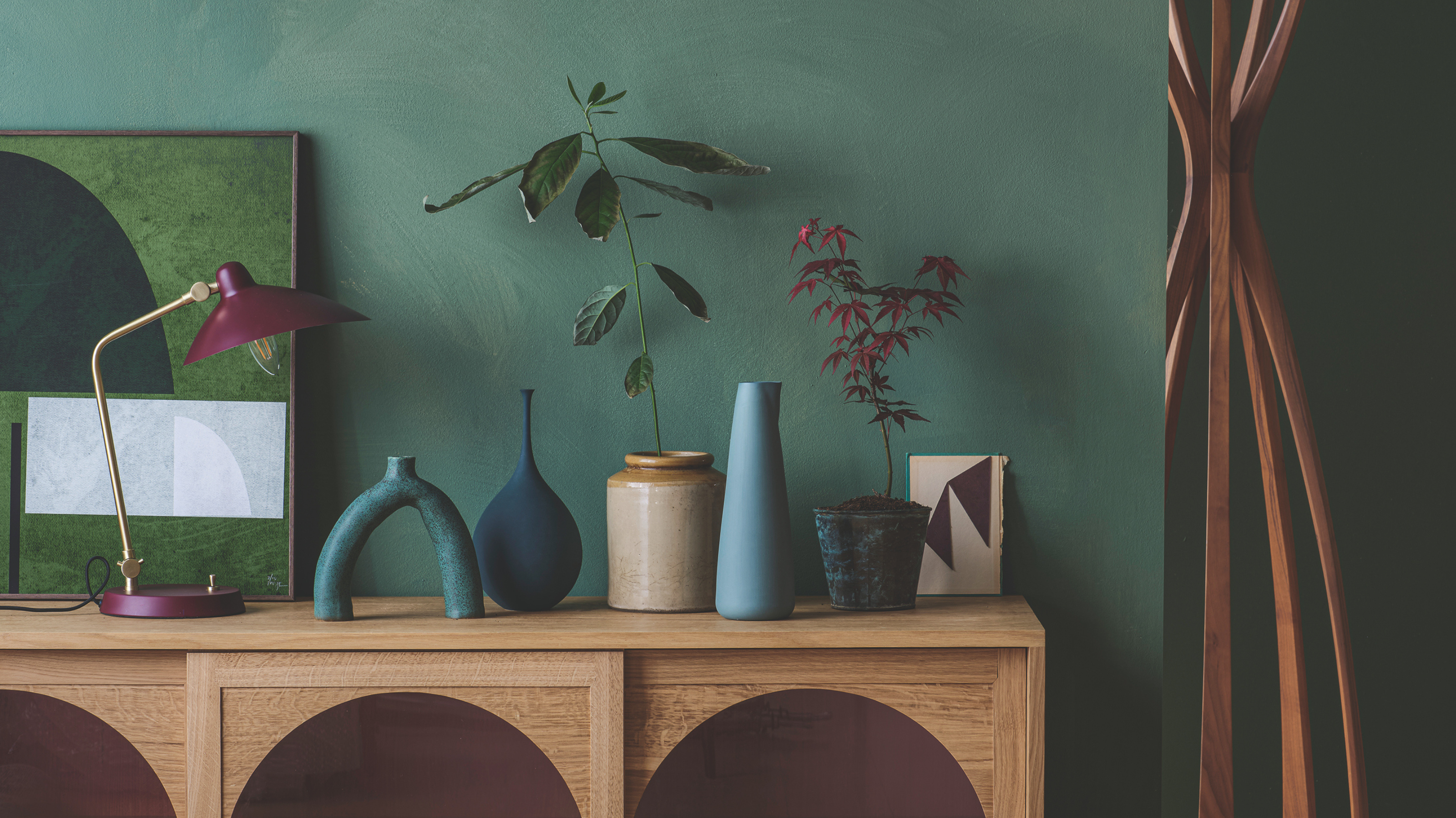 Wooden sideboard with blue ornaments and a red and gold lamp.