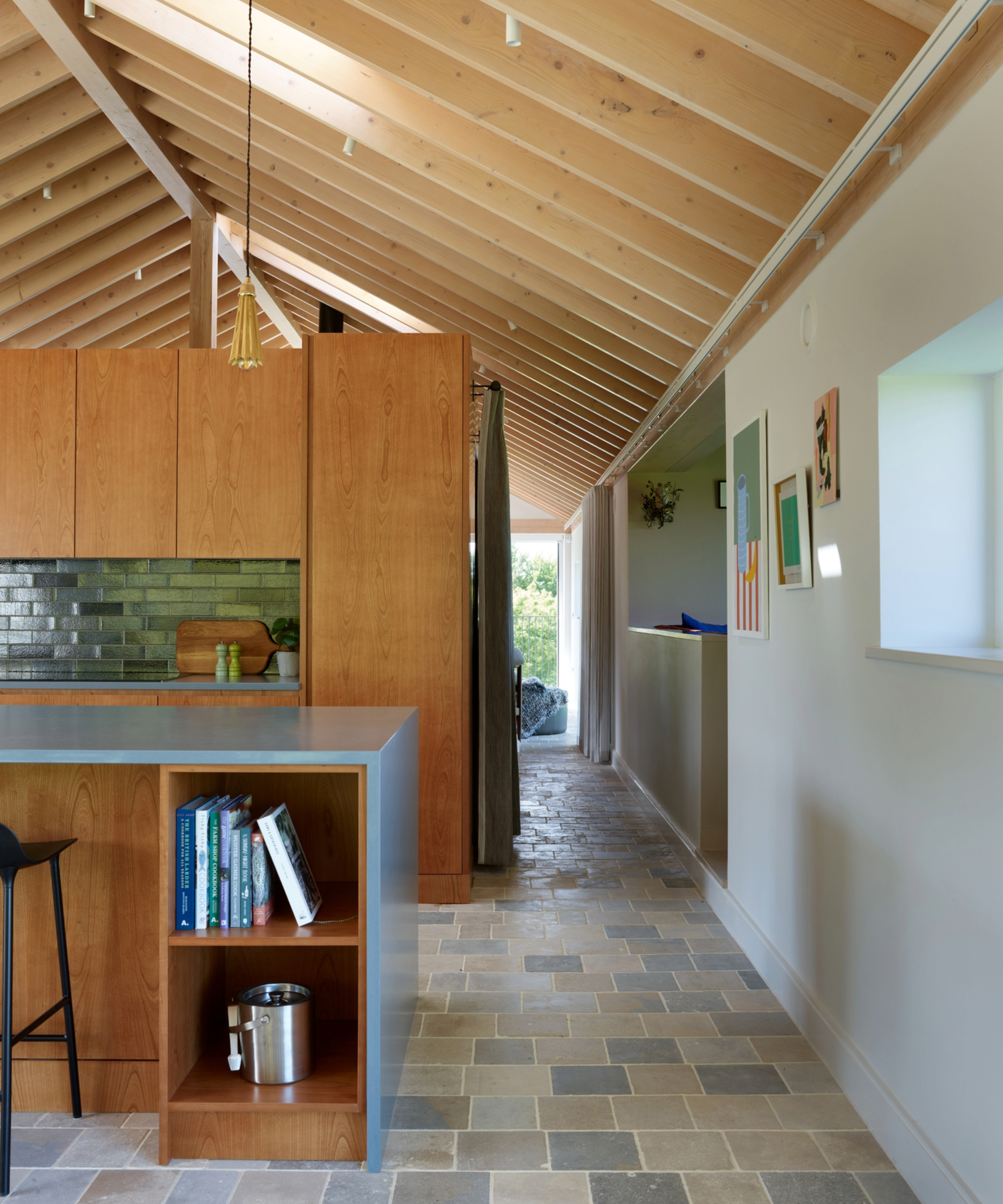 Side of the kitchen with an island with built in bookcase, vaulted ceiling, and blue floor tiles
