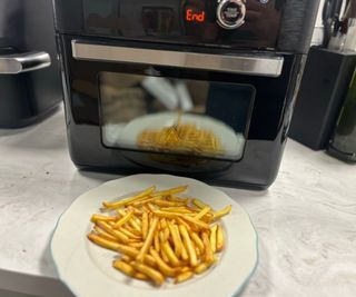 French fries on a plate in front of the Proscenic T31 Air Fryer.