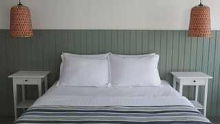 A queen mattress placed on a green bedframe in a sage green bedroom
