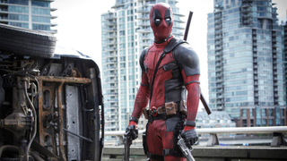 Deadpool stands in front of a turned-over car