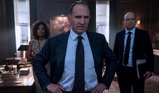 Naomie Harris, Ralph Fiennes, and Rory Kinnear all waiting in an office in No Time To Die.