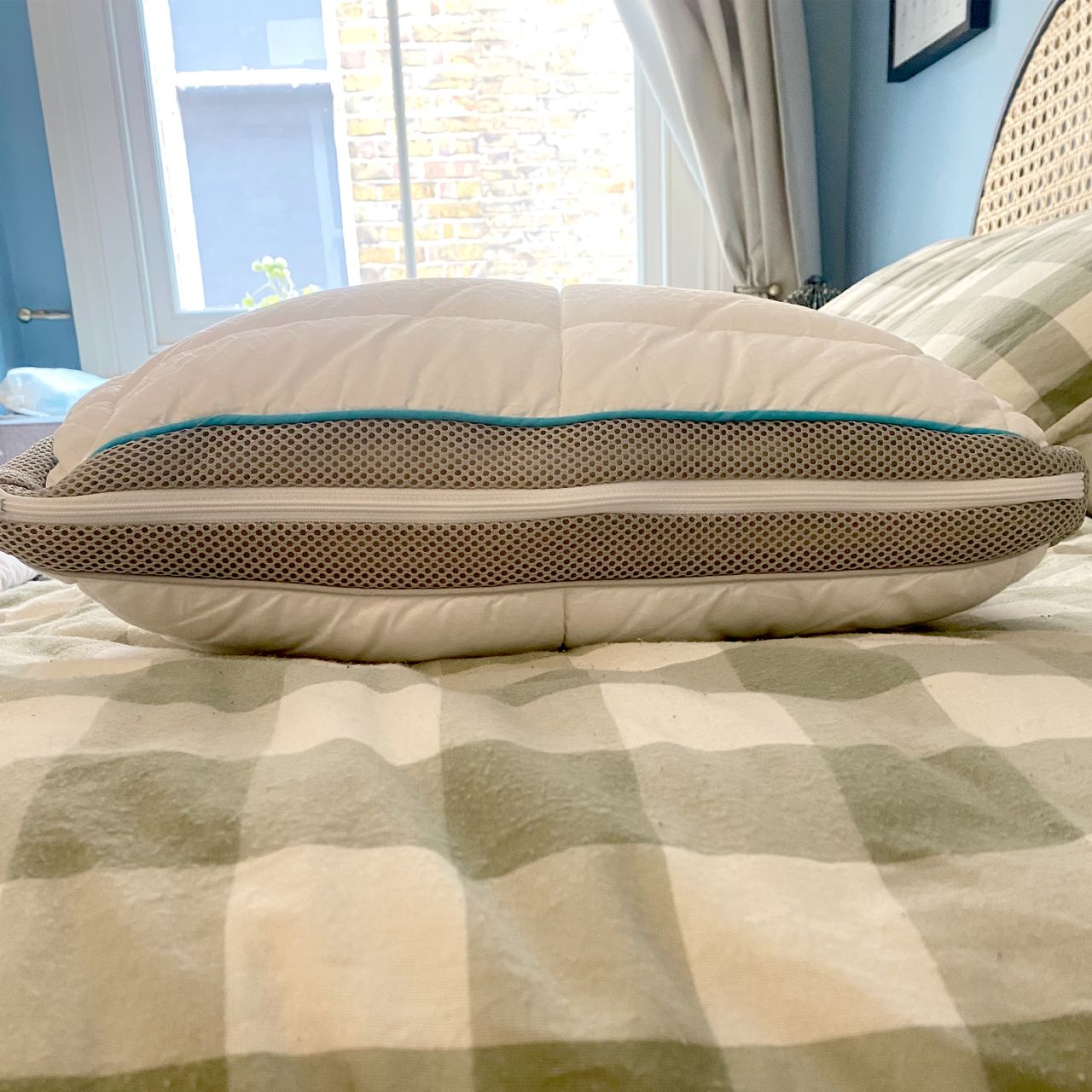 The SImba Hybrid Firm pillow being tested on a bed with a green and white checked duvet