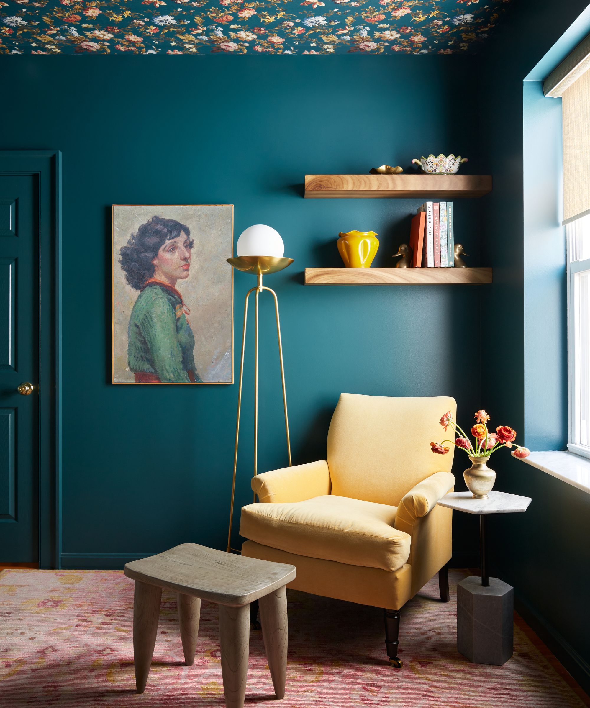 A dark blue room with floral wallpaper on the ceiling, a dusty pink carpet, and an ochre accent chair.