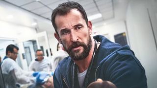 Noah Wyle looks concerned in a hospital hallway