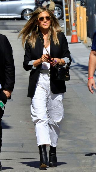 Jennifer Aniston wearing white wide leg jeans, blazer and leather boots on 29 May, 2019 in California