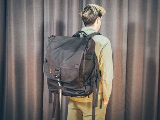 Will Jones, wearing the Chrome Warsaw 2.0, one of the best backpacks for cycling, stands in front of a wall