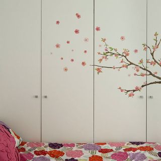 summer bedroom with tree wall motif and floral bed linen