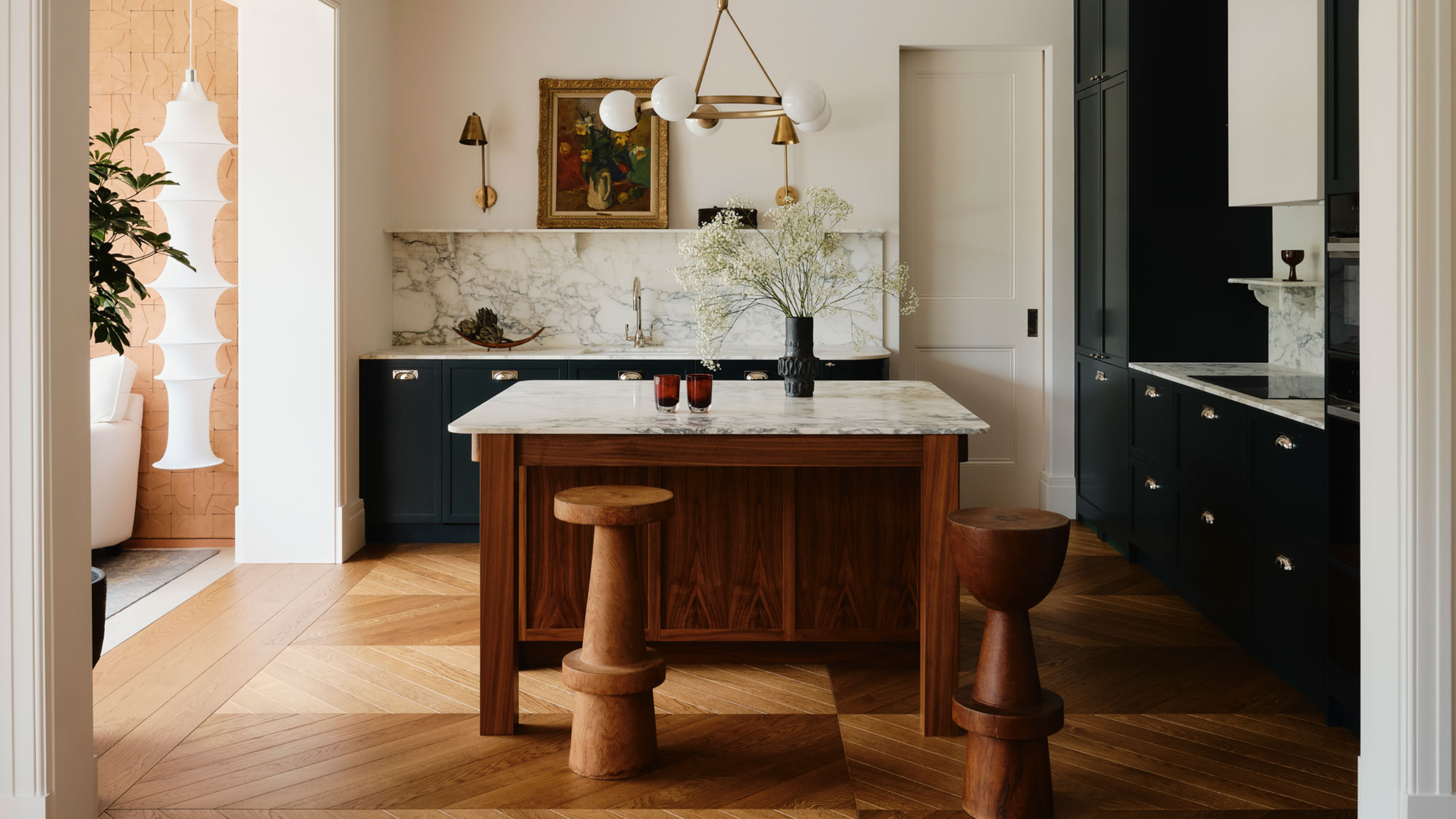 a chevron floored kitchen with a wooden island framed by an architctural arch
