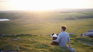Dog and man enjoying sunset in the countryside
