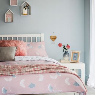 bedroom with bed having pink bedding set and light blue wall