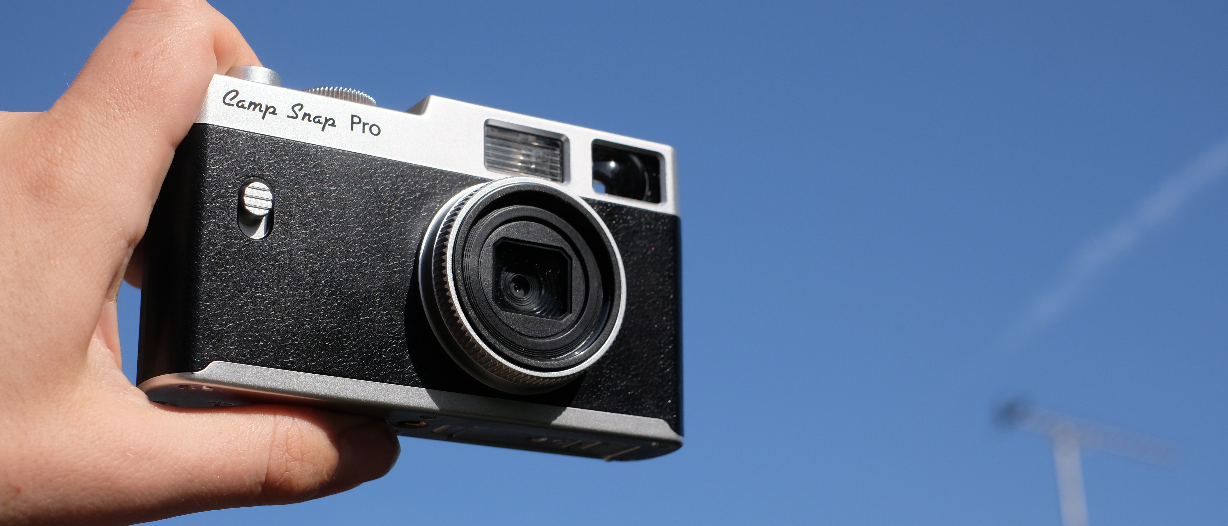Photograph of Camp Snap CS-Pro digital compact camera held in front of a blue, sunny sky