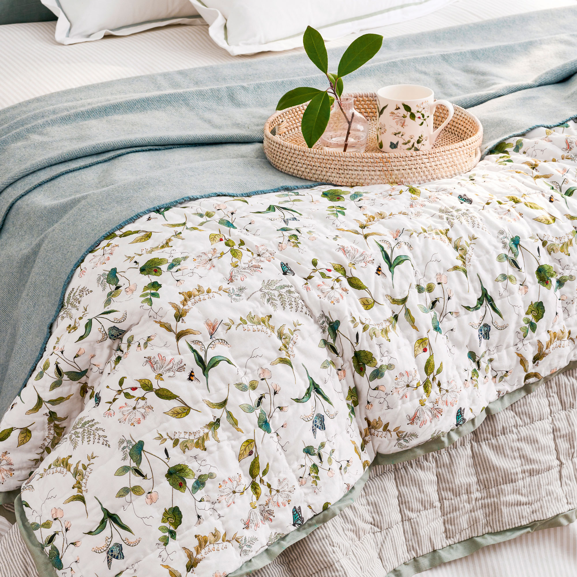 Bed with layered quilt and wicker tray
