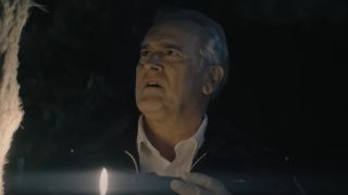 Bruce Campbell as Chief Dandridge looking concerned as he uses his flashlight to look at something in Hysteria!