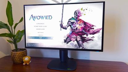 Alienware AW2725Q on desk with Avowed title menu on screen.