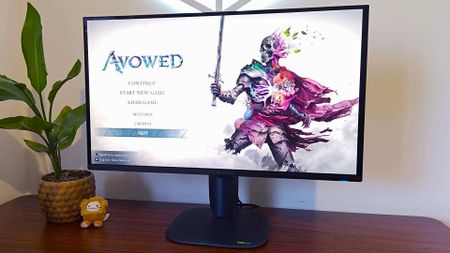 Alienware AW2725Q on desk with Avowed title menu on screen.