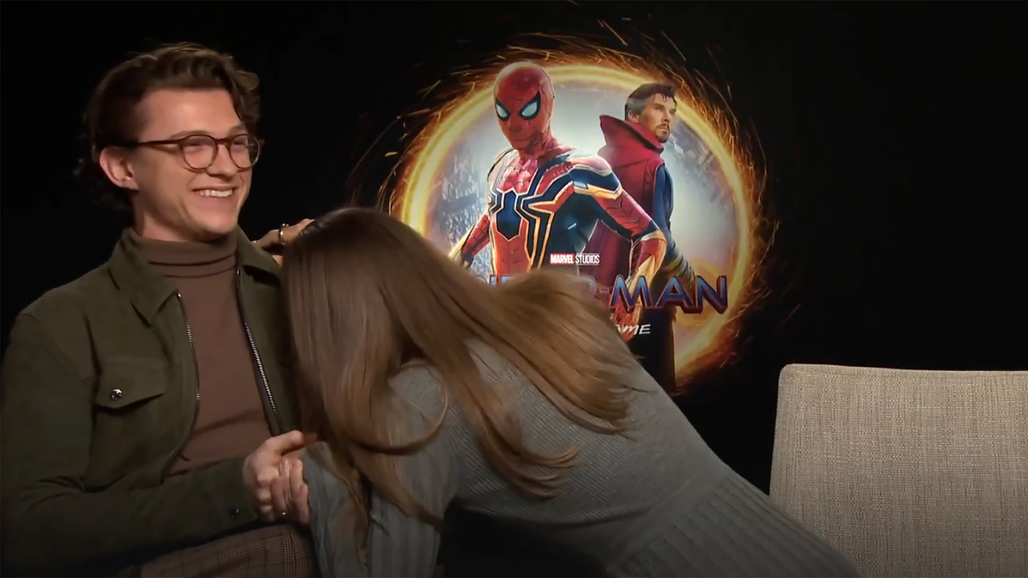 A Screenshot of Zendaya laughing into Tom Holland's arm during the Spider-man: No way home junket.