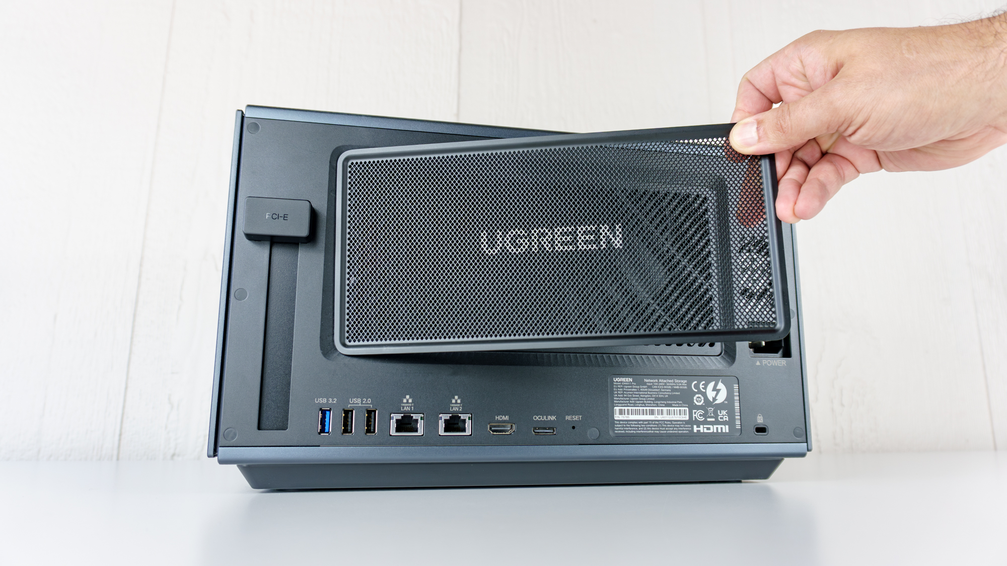 A person removing the mesh cover on the back of the Ugreen iDX6011 Pro NAS