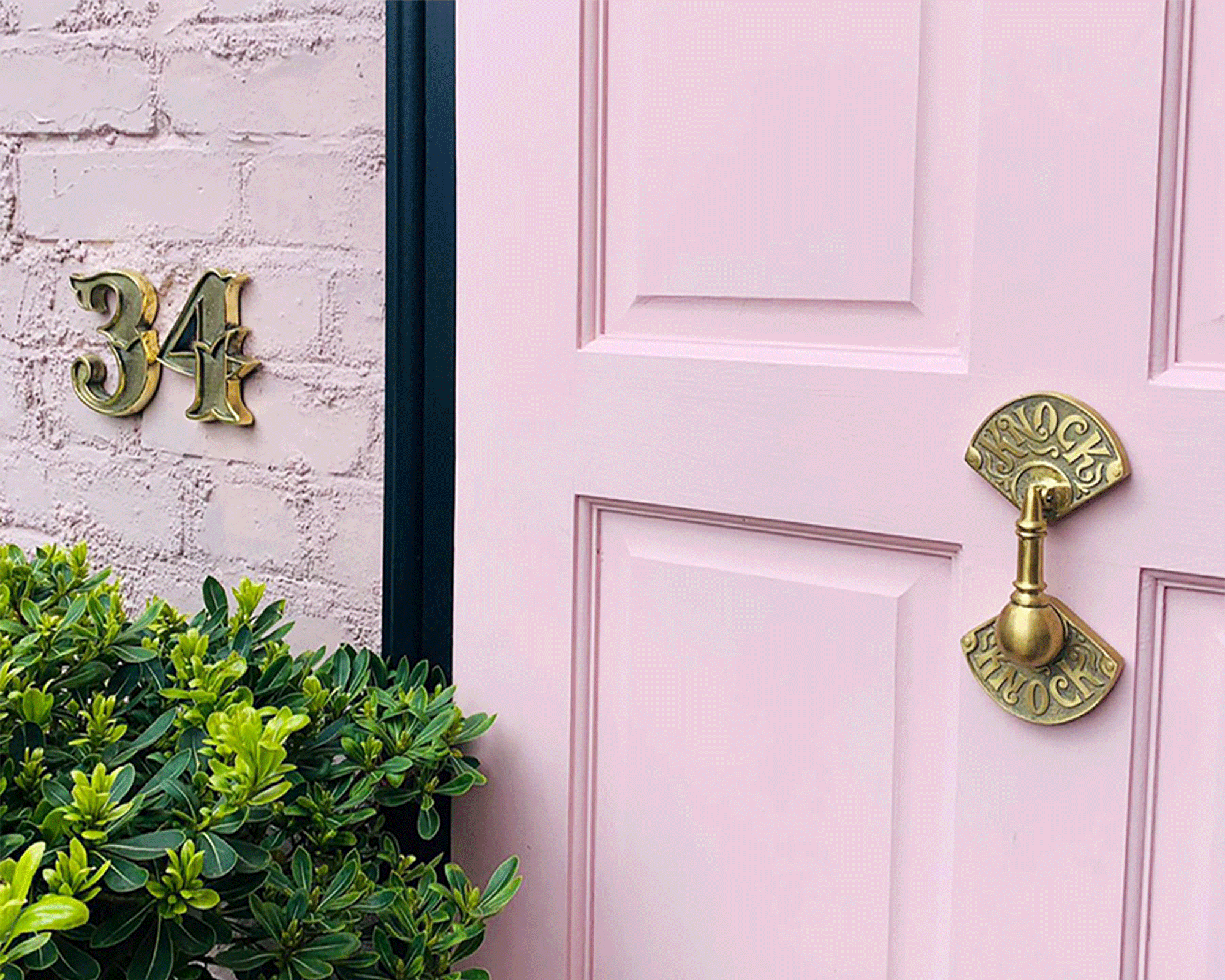 Pink front door with decorative brass knocker and house numbers.